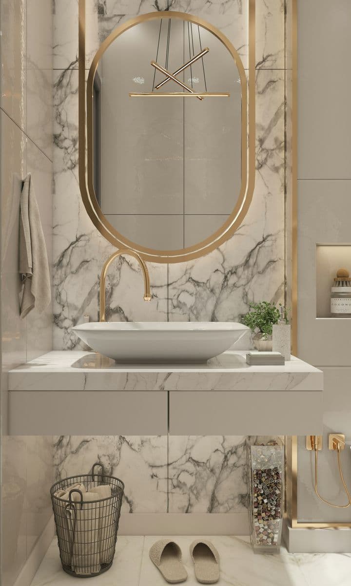 Elegant marble bathroom with a brushed-gold oval mirror and vessel sink