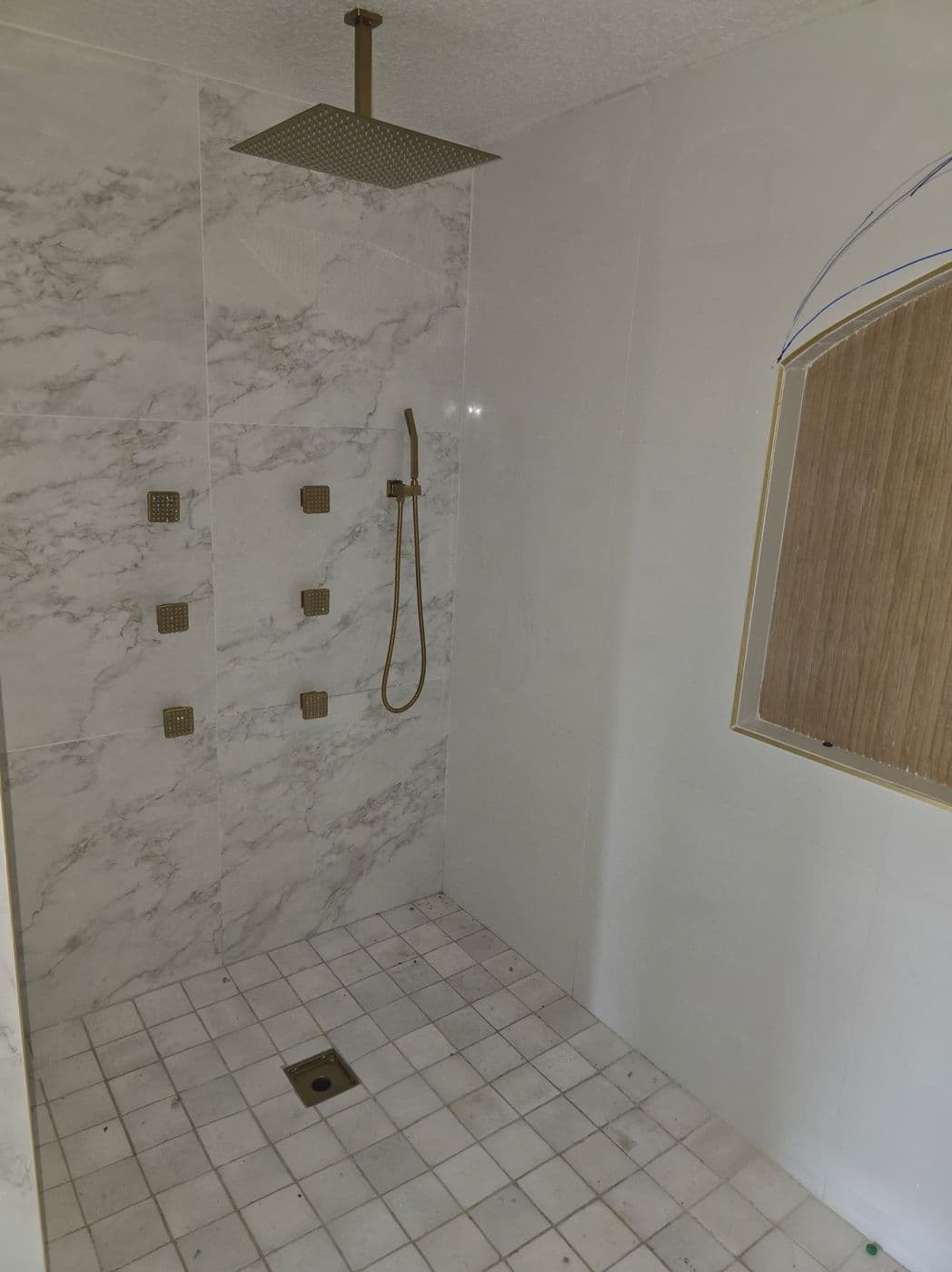 Marble walk-in shower with brushed-brass rain head and body jets