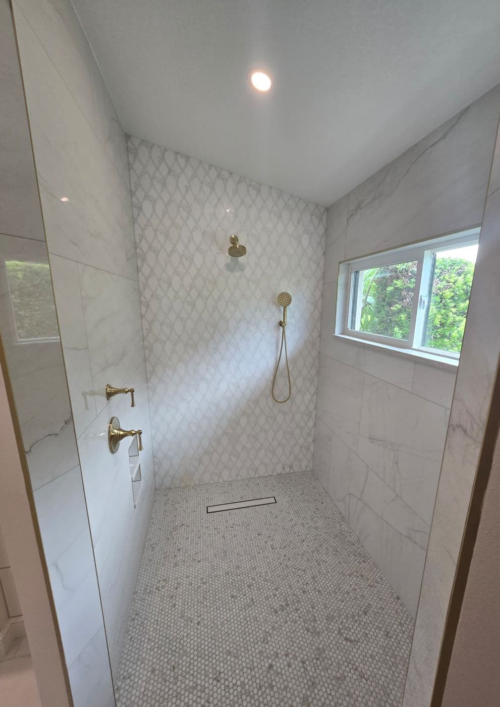 Curbless marble walk-in shower with penny-tile floor and window