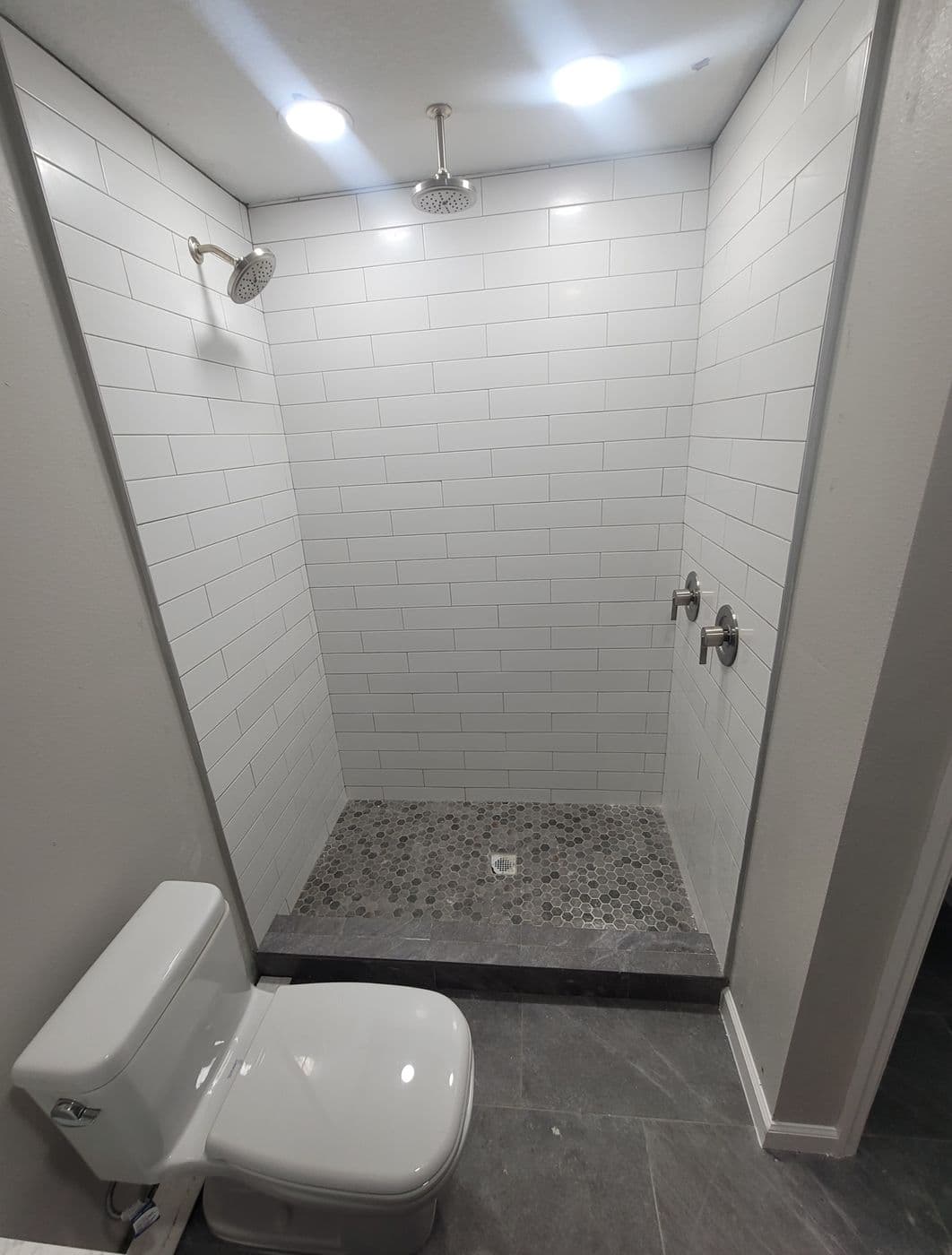 White subway-tile walk-in shower with pebble-mosaic floor