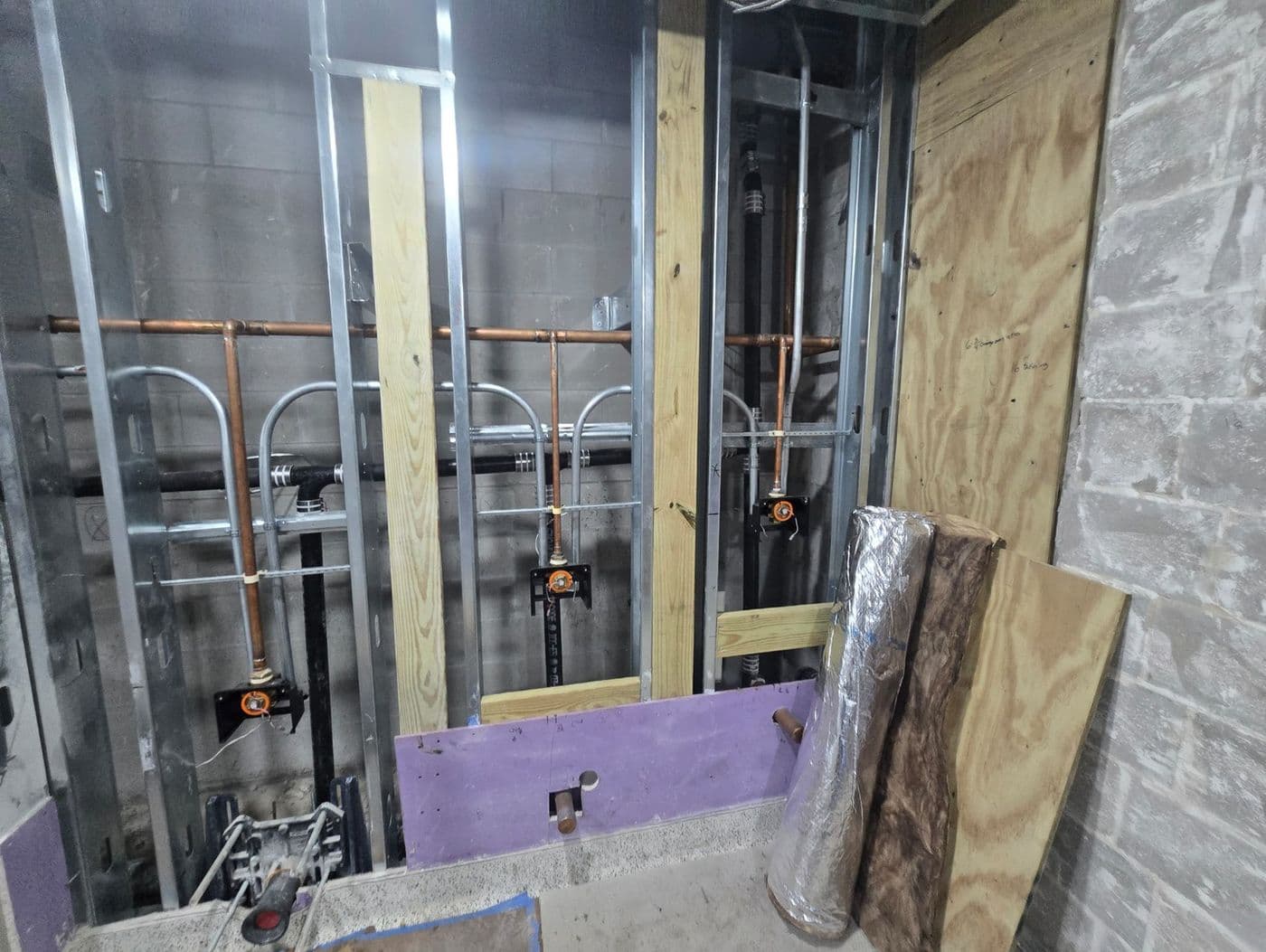 Carrier-mounted fixture rough-in for a commercial restroom wall