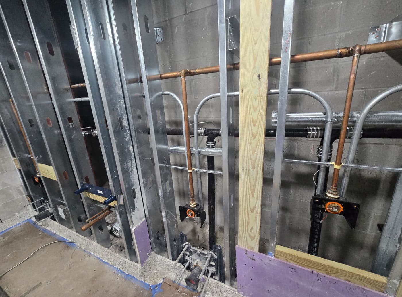 Copper water supply and DWV drain rough-in on a steel-stud wall
