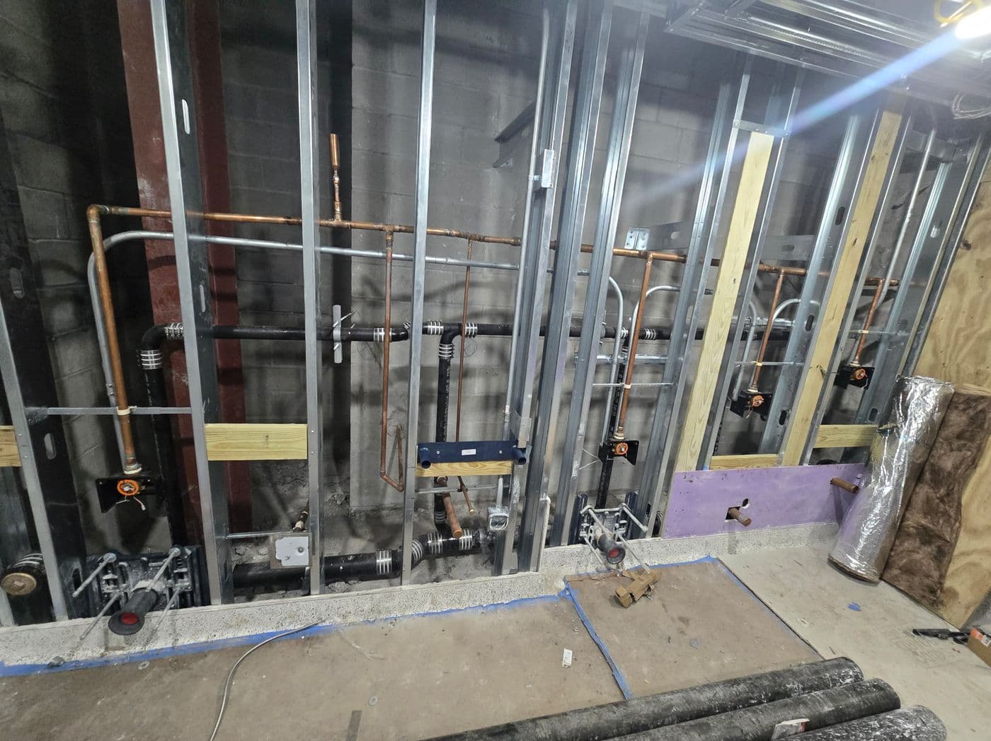 Copper and PVC repipe across a framed multi-bathroom wall